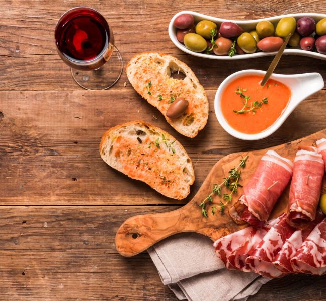 spanish tapas and red wine on wooden table, top view